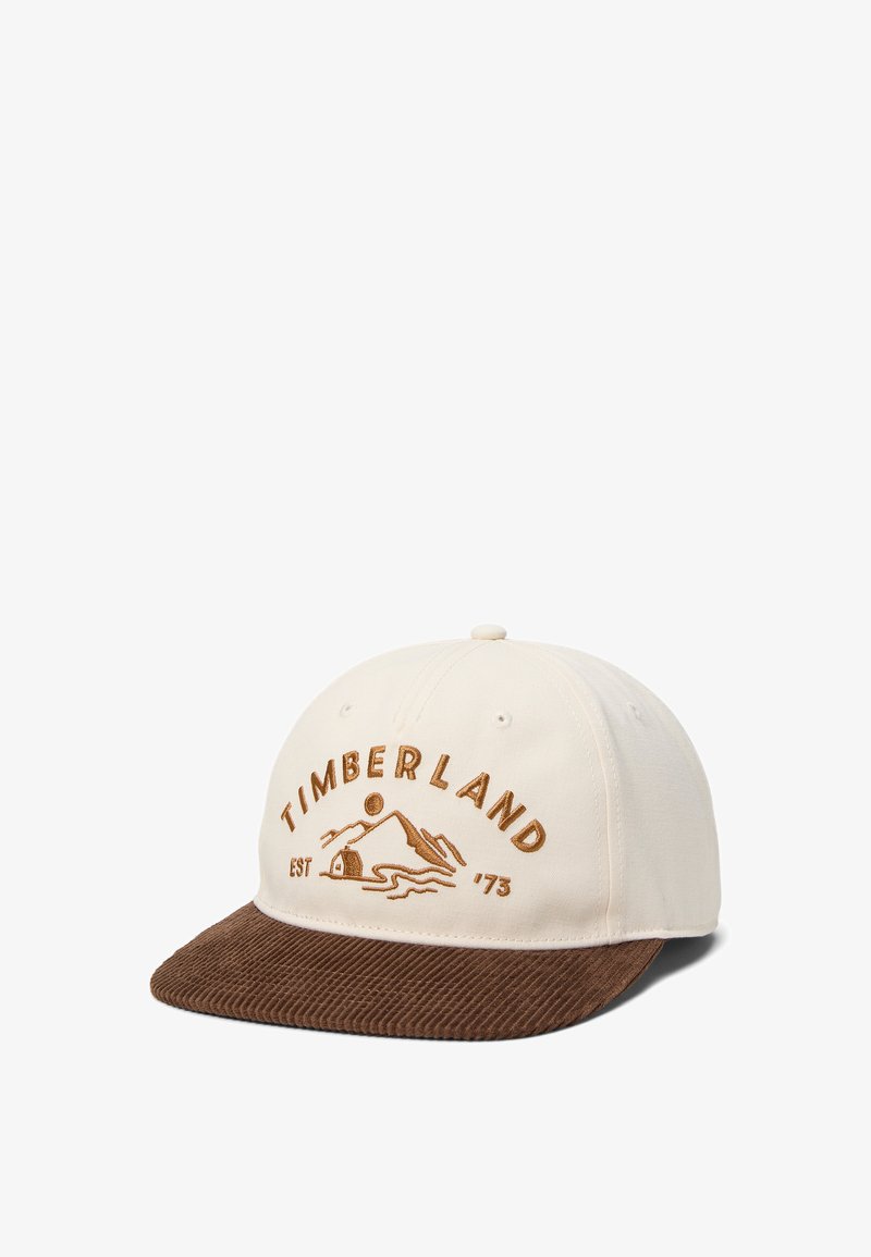 Casquette de baseball beige avec visière en velours côtelé marron, présentant le texte brodé "Timberland" et un logo de montagne avec "EST '73".