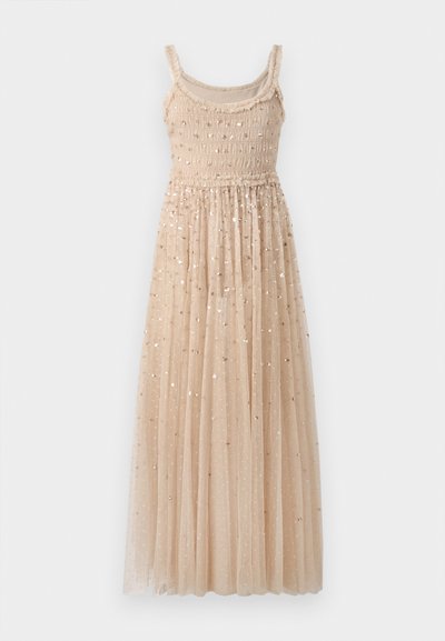 Abito lungo beige con corpino arricciato e spalline sottili. Presenta una gonna di tulle a strati con paillettes dorate sparse in tutto il tessuto.