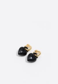 Pendientes de aro dorados con charm en forma de corazón negro sobre un fondo blanco, mostrando vistas frontal y lateral.