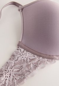 Šviesiai violetinė paminkštinta liemenėlė su gėlių n�ėrinių detalėmis apačioje, pasižyminti lygiu audiniu ir satino akcentais kraštuose ir petnešėlėse.