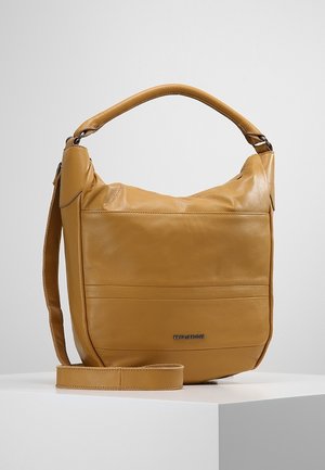 Beżowa skórzana torebka na ramię z krótkim uchwytem, długim regulowanym paskiem i naszywką z logo z przodu na białej powierzchni.