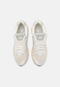 Weiße Mesh-Laufschuhe mit grauen Akzenten, ausgestattet mit Schnürverschluss, gepolstertem Schaft und Gummisohle. Für Komfort und Unterstützung ausgelegt.