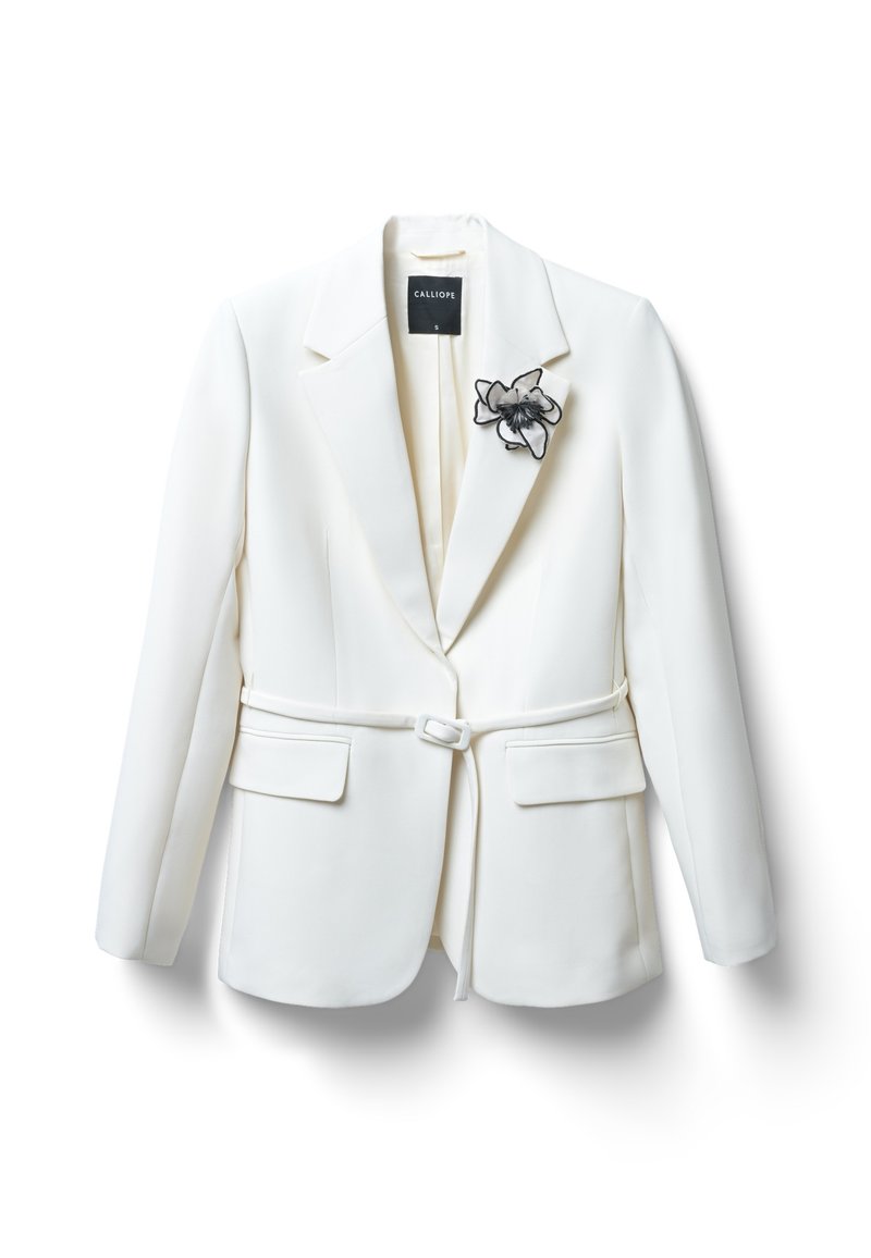 Weißer maßgeschneiderter Blazer mit Reverskragen, taillierter Taille und Fronttaschen. Mit einer schwarzen Blumenbrosche auf der linken Seite.