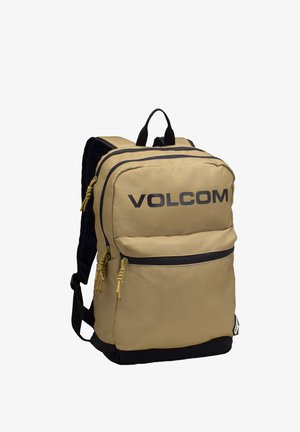 Mochila de nailon beige con acentos y cremalleras negras, que cuenta con un gran compartimento principal, un bolsillo frontal y correas ajustables y acolchadas.