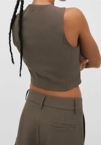 Braunes kariertes ärmelloses Crop-Top, figurbetontes Design mit hohem Halsausschnitt, kombiniert mit passenden maßgeschneiderten Hosen mit Seitentaschen.