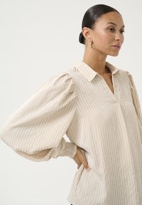 Beige blouse met verticale strepen, voorzien van een kraag, pofmouwen en geplooide manchetten. Zachte stof met een vloeiende uitstraling.