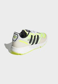 Neon dzeltenas un melnas sporta apavi ar sietu augšējo daļu, balto zoli un trim melnajām svītrām. Iekļauj gludas, teksturētas akcentus un šņorēšanu.