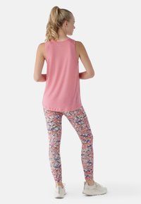 Top senza maniche rosa con una texture liscia, abbinato a leggings a fantasia multicolori che presentano una combinazione di sfumature rosa, bianche e blu.