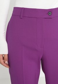 Livliga lila skräddarsydda byxor med en mjuk textur, som har en enkel knappstängning och sidofickor. Platt framsida med bälteshäften.