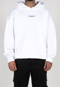 Hvid hoodie lavet af blødt stof, med en front kangaroo-lomme, snørehætte og grafisk tekst på brystet.
