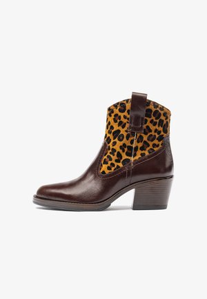 Bota de tobillo de cuero con un acabado pulido marrón y parte superior de textil con estampado de leopardo. Presenta una punta cuadrada y un tacón apilado.