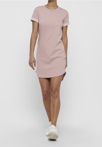 Rentokas kaula avaneva lyhythihainen mekko pehmeästä pastellivärisestä puuvillasta, jossa on käärittävät hihansuut, pyöreä kaula-aukko ja hieman kaareva helma.