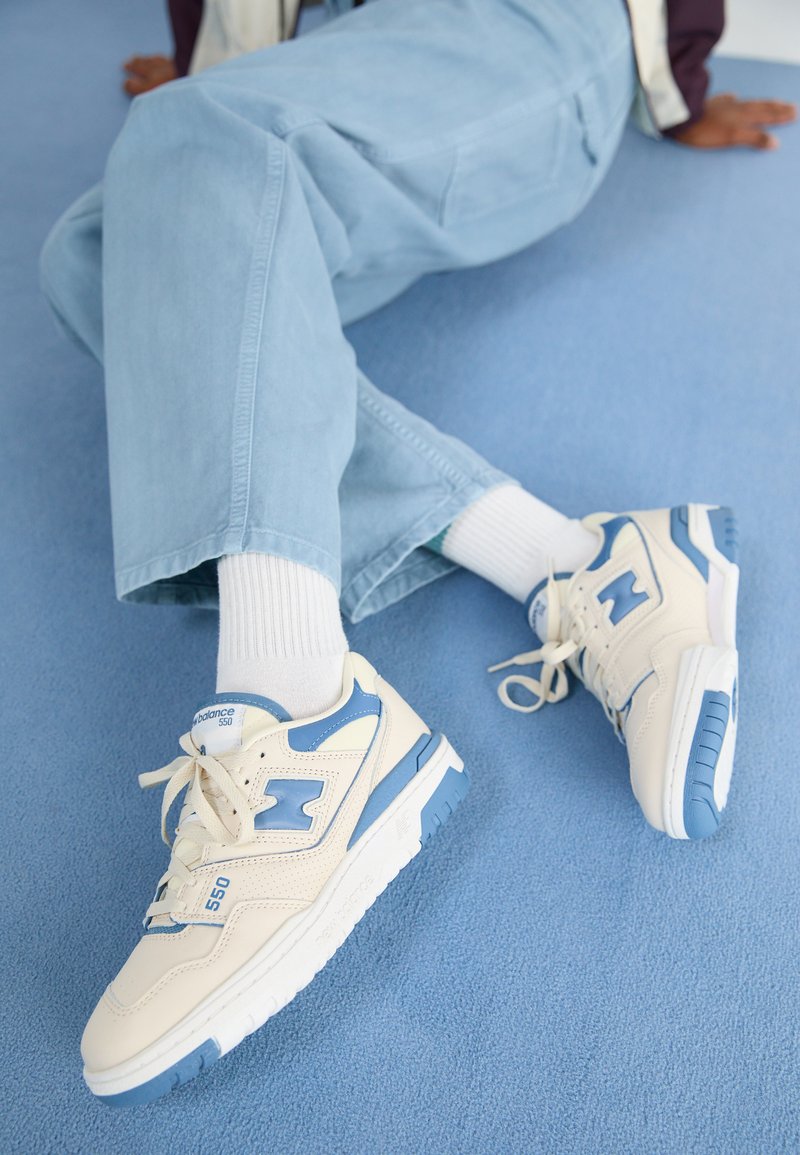 Sneaker color crema con accenti blu, con tomaia in pelle texturizzata, lacci e suola in gomma con motivo.