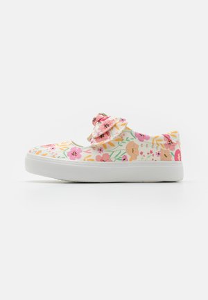 Des chaussures à enfiler en toile florale avec une semelle en caoutchouc blanche, des fleurs rose pastel, des feuilles vertes et un nœud en tissu assorti sur le dessus.