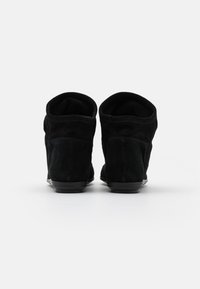 Černé semišové kotníkové boty s kulatou špičkou, nízkým podpatkem a měkkou vnitřní podšívkou, které mají hladký povrch a čistý design.