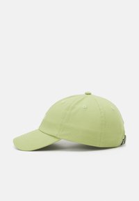 Green cotton baseball cap with a curved brim, six-panel design, and embroidered detail on the front. Adjustable strap at the back.