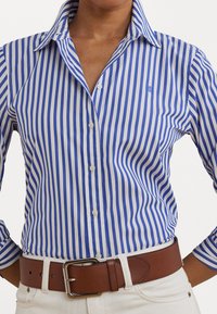 Blue and white striped button-up shirt with a pointed collar and long sleeves, featuring a small logo embroidered on the chest.