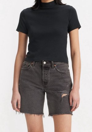 Schwarzes Baumwoll-T-Shirt mit kurzen Ärmeln und hohem Ausschnitt, kombiniert mit grauen hoch taillierten Jeansshorts mit ausgefranstem Saum und Used-Effekten.