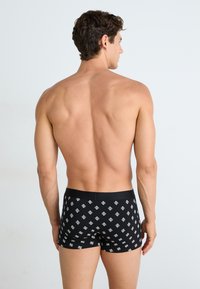 Boxer-briefs noirs avec un motif en losange blanc. Fabriqués à partir d'un matériau extensible, conçus pour s'adapter de près et confortablement.