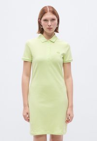 Robe polo de couleur vert clair, confectionnée en coton. Comprend un col, des manches courtes, une patte de boutonnage et un petit logo brodé sur la poitrine.