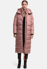 Long, pink puffer coat with hood, quilted design, side pockets, orange accent details, and a full zipper closure. Worn over black clothing.