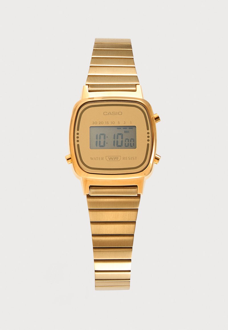 Χρυσό ψηφιακό ρολόι Casio με ορθογώνιο καντράν που δείχνει ώρα 10:10, μεταλλικό λουράκι και σήμανση αντοχής στο νερό.