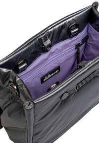 Intérieur d'un sac rembourré noir avec une doublure violette, comportant une poche zippée et une étiquette de marque. Texture lisse et accents métalliques visibles.