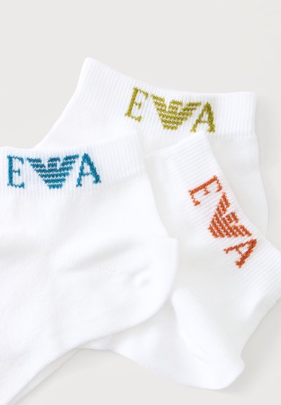 Trois chaussettes blanches cheville avec des logos EA colorés en bleu, vert et orange sur les bords, posées sur une surface claire.