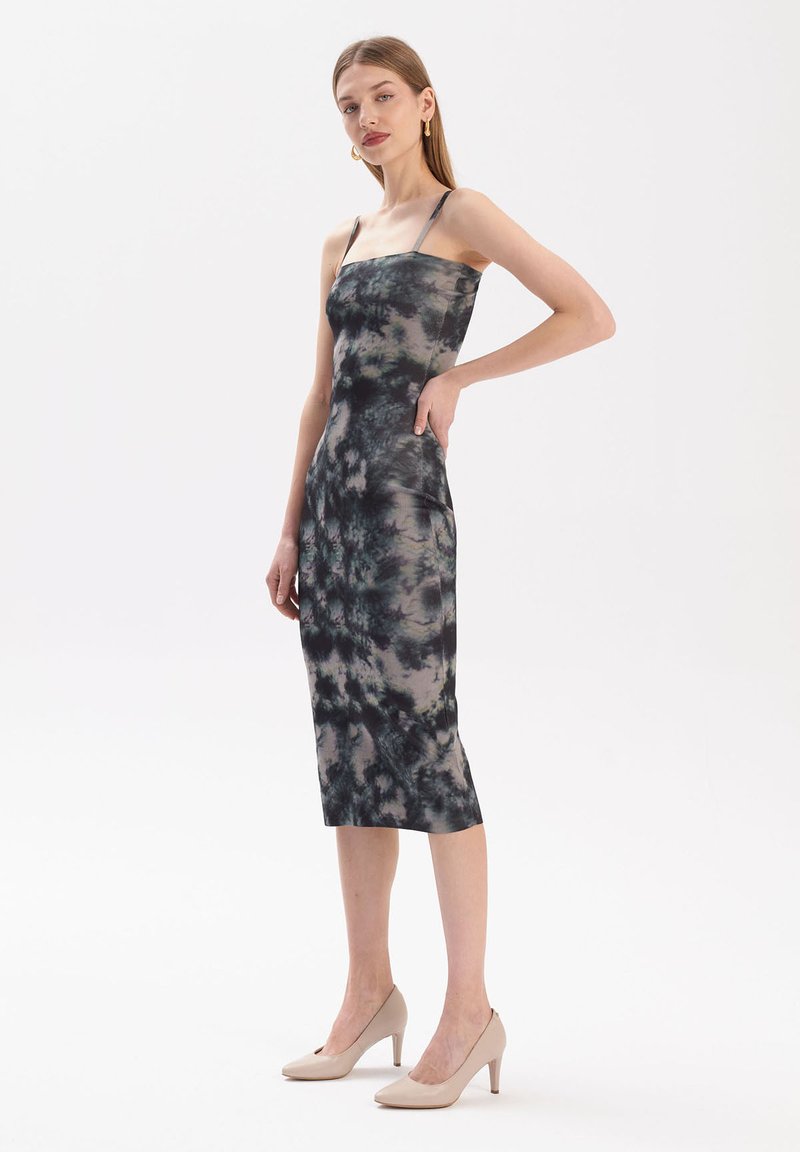 Czarna i szara sukienka midi z wzorem tie-dye, z cienkimi ramiączkami, dopasowanym krojem, gładką fakturą i prostym dołem. Noszona z beżowymi szpilkami.