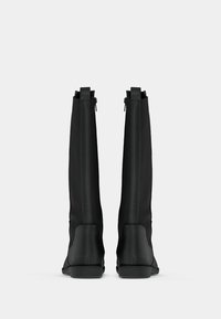 Čierne čižmy nad kolená z hladkého materiálu s priliehavým dizajnom, zadnými zipsami a plochými gumovými podrážkami. Jednoduchý a elegantný siluet.