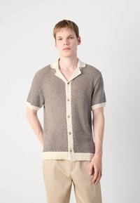 Short-sleeve knit shirt in brown with a textured pattern, cream-colored collar and buttons, and ribbed cuffs and hem.