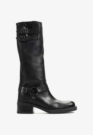 Czarny skórzany but do połowy łydki z niskim, szerokim obcasem, dwoma klamrami u góry oraz ozdobnym paskiem z metalowymi elementami wokół kostki.