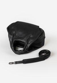 Zwarte leren tas met een zachte textuur en een slungelige vorm; inclusief een afneembare schouderband. Voorzien van een ritssluiting en een open bovenkant design.