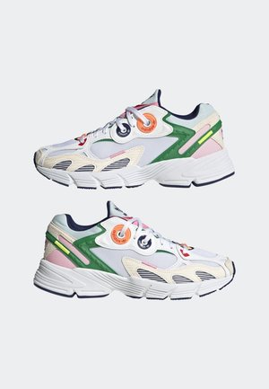 White athletic sneakers with green, pink, and beige accents, featuring circular Adidas logos near the laces and thick, textured soles.