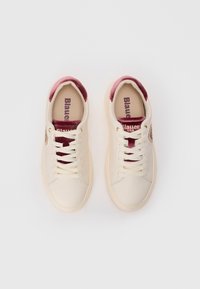 Baskets créme avec des lacets blancs, languette et col en velours bordeaux, et "Blauer" imprimé à l'intérieur sur un fond blanc.
