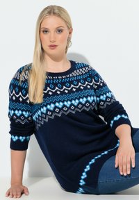 Mörkblå tröja med ett geometriskt Fair Isle-mönster i nyanser av blått, vitt och grått. Ribbad mudd och nederkant; avslappnad passform.