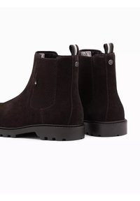 Botas Chelsea de ante negro con paneles laterales de malla texturizada, lengüetas en el talón de contraste y suelas de goma resistentes. Presentan puntera redonda y tacón ligero.