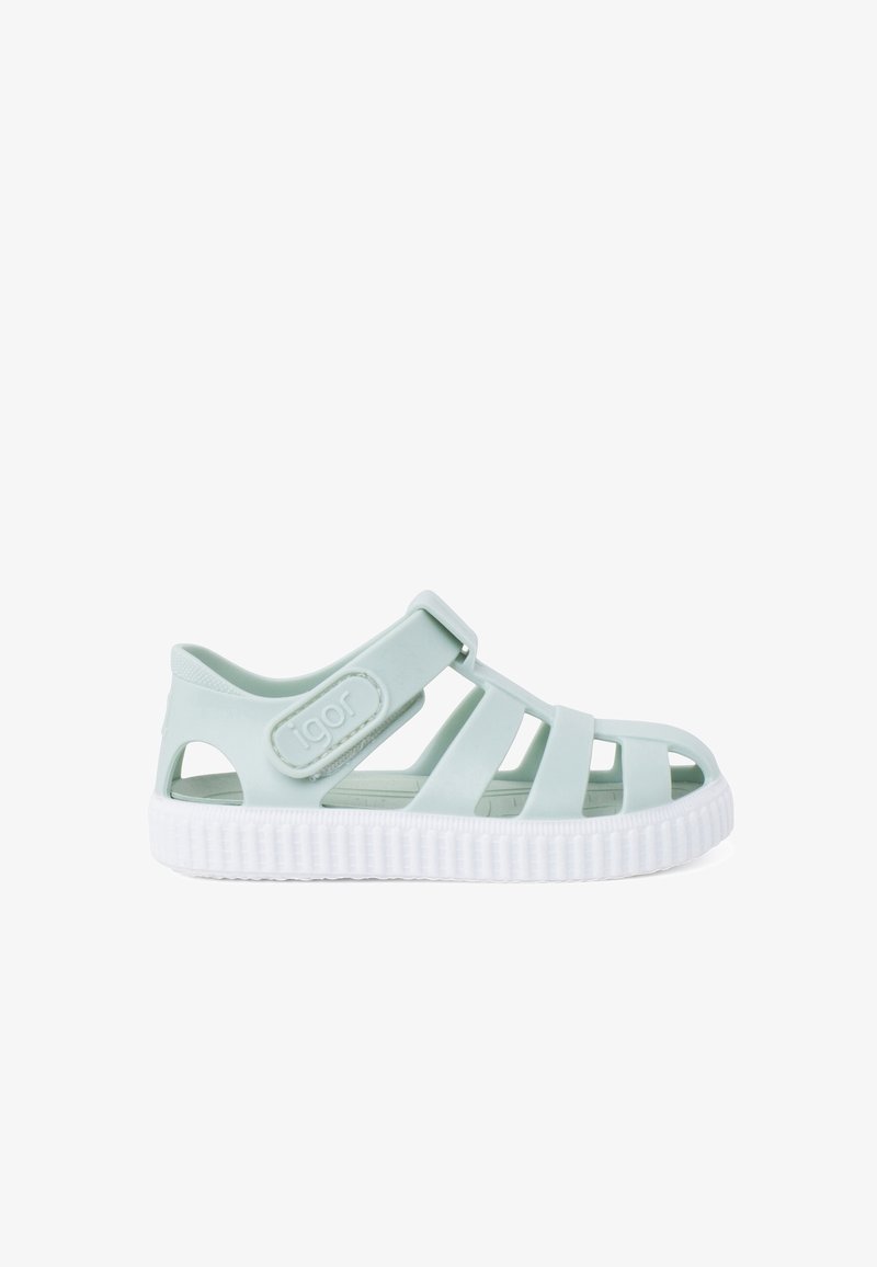 Hele roheline plastist sandaal, millel on suletud varvas, avatud küljed, reguleeritav rihm ja tekstuuriga valge tald, millel on sooned.