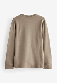 Maglietta a maniche lunghe a coste in beige tenue. Presenta un coltondo e polsini aderenti. Texture morbida, cuciture uniformi e linee pulite.
