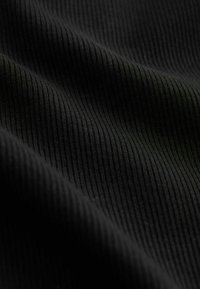 Tissu noir côtelé avec une texture lisse ; les plis créent des ombres subtiles, mettant en valeur le motif côtelé vertical à travers la surface.