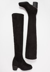 Botas negras sobre la rodilla, hechas de suave ante, con un bajo tacón cuadrado, que presentan una textura lisa y líneas elegantes sin herrajes visibles.