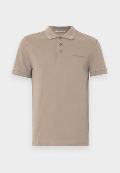Polo tričko v svetlo hnedej zmesi bavlny, s trojmiestnym zapínaním, krátkymi rukávmi a nenápadným vyšitým logom na hrudi.