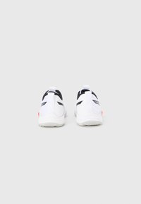 Λευκά αθλητικά παπούτσια με μαύρες λεπτομέρειες, που διαθέτουν ομαλή υφή, στρογγυλεμένο σχήμα, διχτυωτό επάνω μέρος και κόκκινη πινελιά στη φτέρνα.