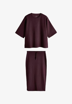 Mørkelilla sæt med en løs top med korte ærmer og en rund hals samt et højtaljet midinederdel med snøre foran.