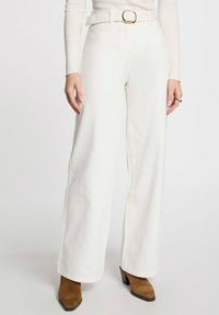 Jeans anchos blancos de mezclilla, con una cintura alta, un cinturón con hebilla dorada y costuras rectas. La tela parece suave y resistente.