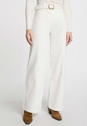 Jeans anchos blancos de mezclilla, con una cintura alta, un cinturón con hebilla dorada y costuras rectas. La tela parece suave y resistente.