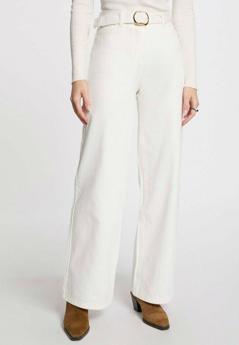 Jeans anchos blancos de mezclilla, con una cintura alta, un cinturón con hebilla dorada y costuras rectas. La tela parece suave y resistente.
