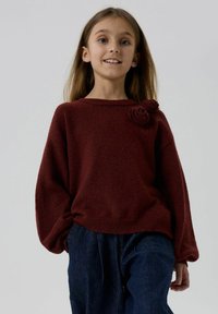Burgundy kudum скид#$__with relaxed fit ja laiad varrukad, mille vasakus õlas on tekstuuriga lillede aksessuaar. Kombineeritud tume teksadega.