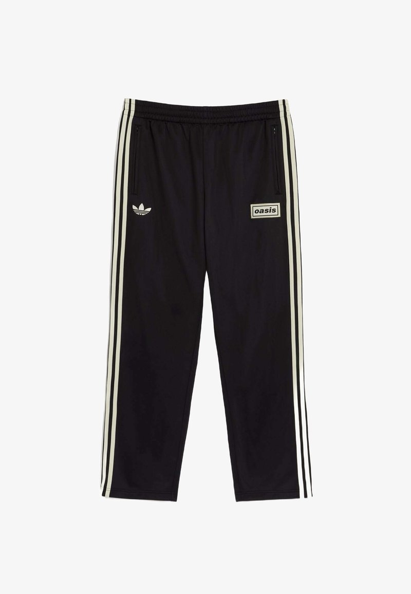 Zwarte sportbroek van soepel materiaal, met witte drie-strepen accenten, een geborduurd logo en een rechthoekig label met de tekst 'oasis.'