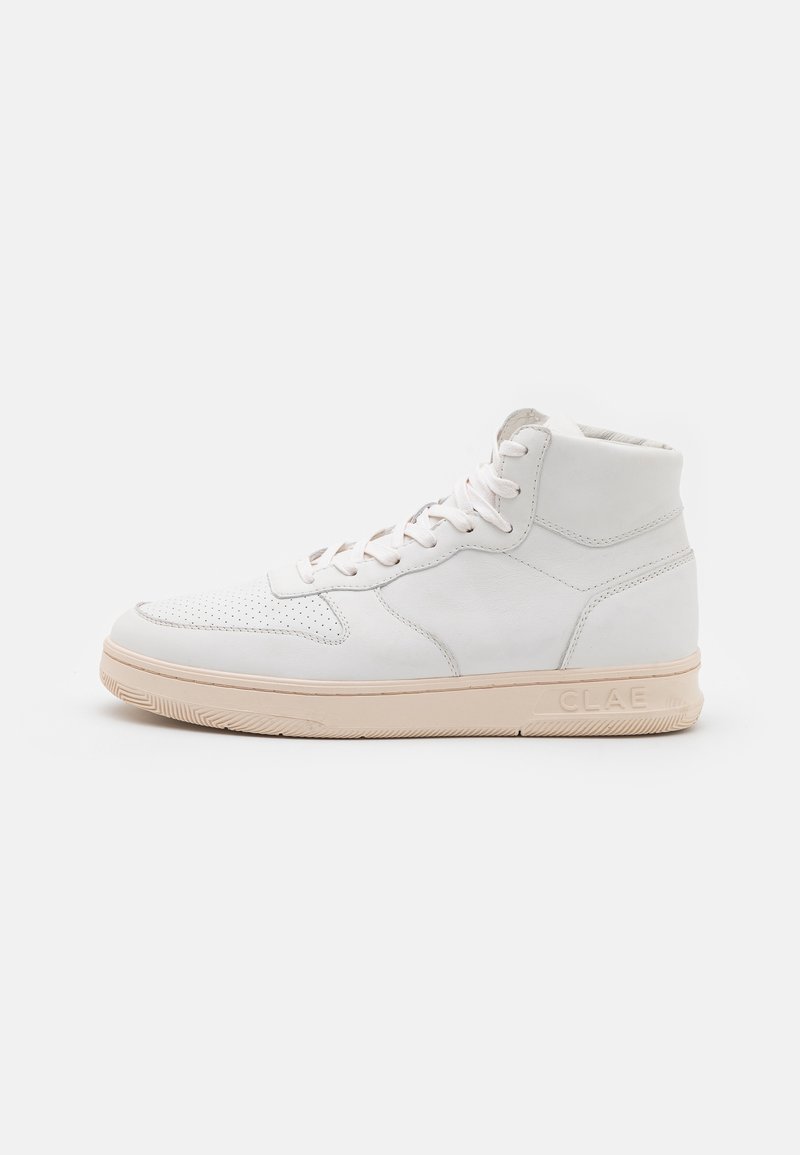 Zapatilla alta blanca con suela beige, área de puntera perforada, parte frontal con cordones y nombre de la marca "CLAE" visible en el costado de la suela.